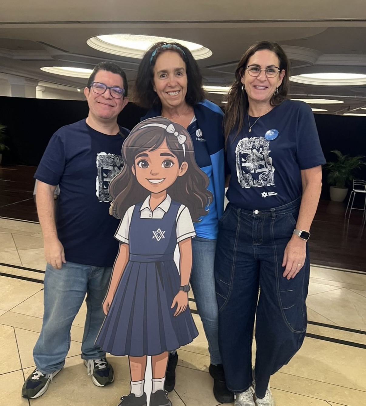 Miembros del Consejo del Fondo de Becas junto a la figura de una alumna en uniforme escolar, símbolo de la campaña